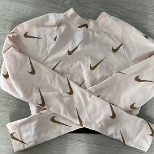 Tue shirt is a long sleeved from Nike with the color pink and gold .